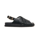 A black leather slide sandal with a wide criss-cross strap design across the foot and a single adjustable ankle strap with a gold-tone buckle, shown in a side profile on a white background. Podiatry endorsed comfort. Minx wellness footbed