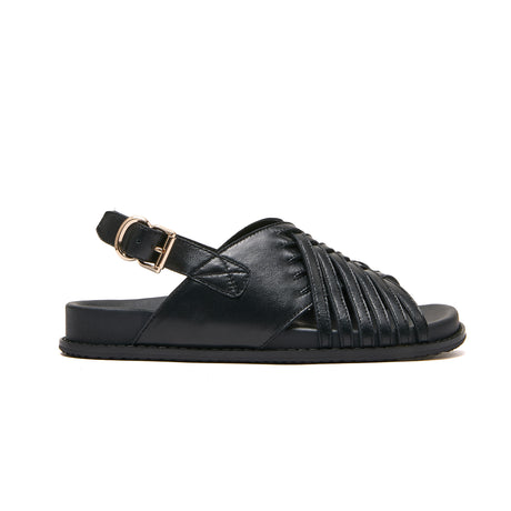A black leather slide sandal with a wide criss-cross strap design across the foot and a single adjustable ankle strap with a gold-tone buckle, shown in a side profile on a white background. Podiatry endorsed comfort. Minx wellness footbed