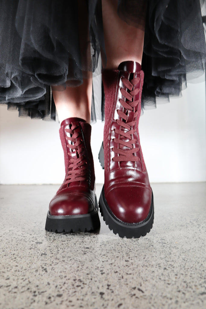 Red combat boots worn with a black tulle skirt on a light background